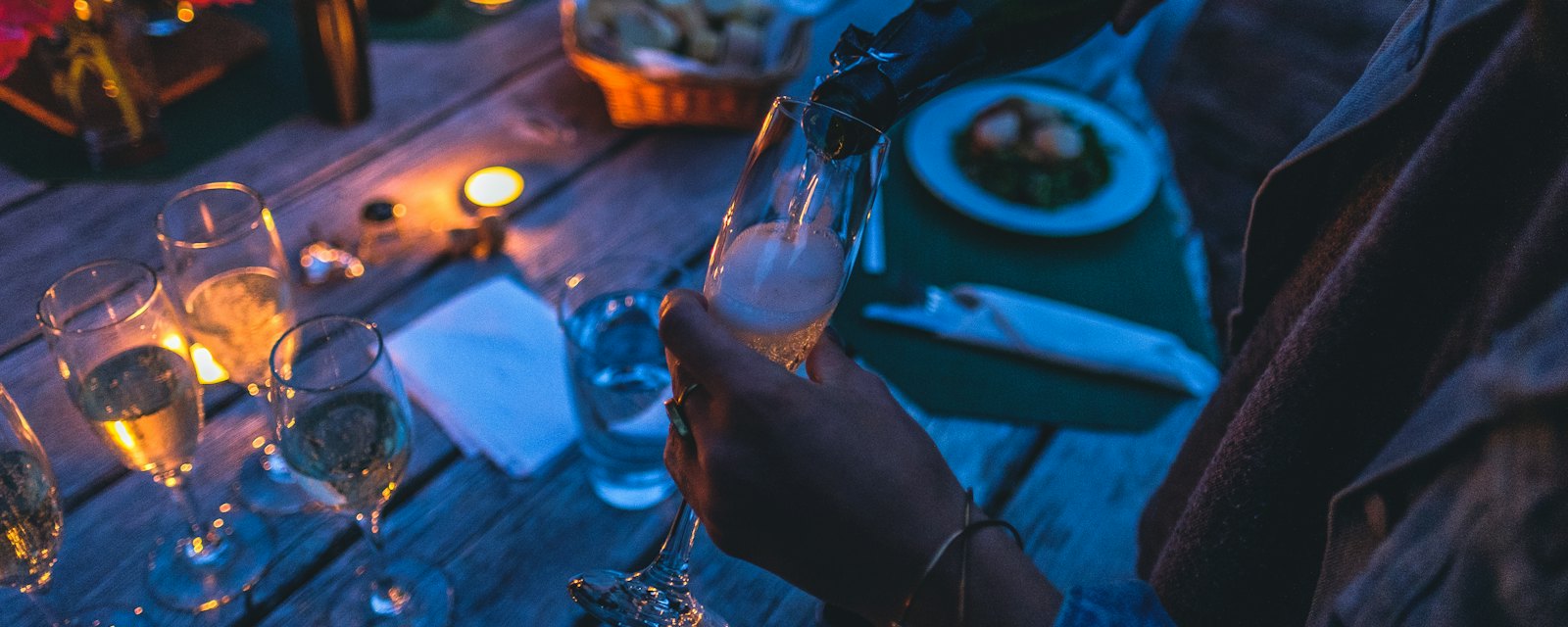 Glasses of champagne being poured at a candlelit table