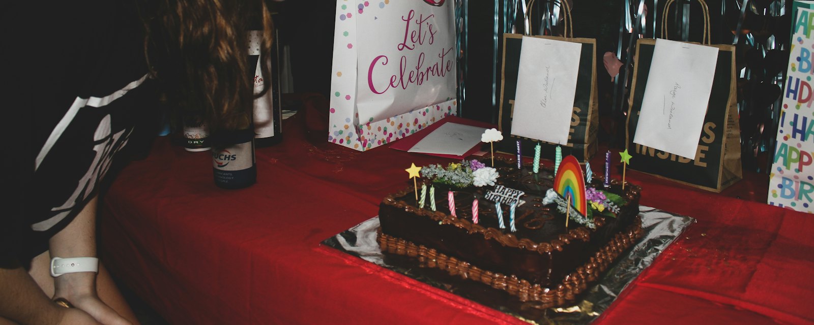 A birthday cake with lit candles on a party table