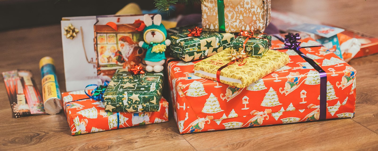 Wrapped Christmas presents piled on a wooden floor