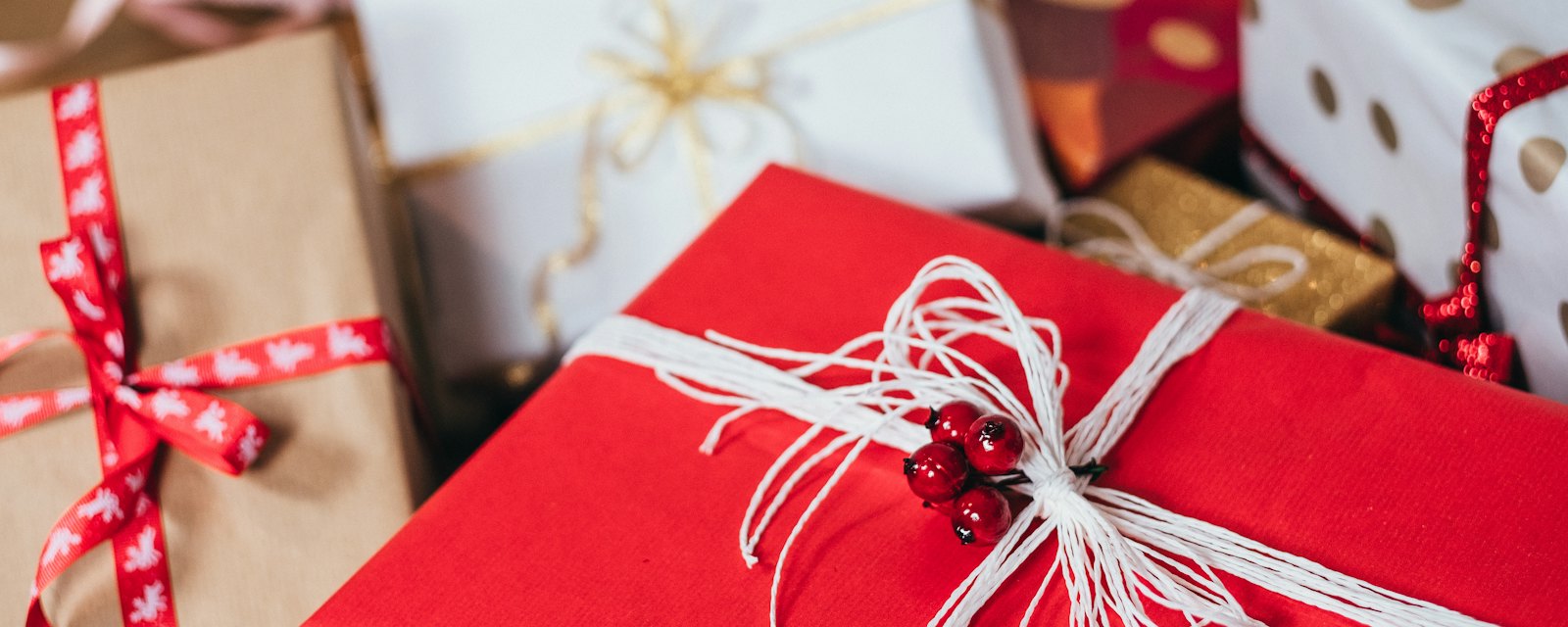 A pile of wrapped presents with red and white ribbons