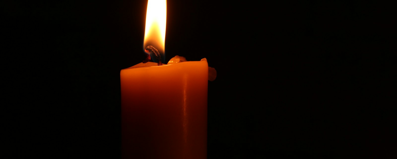 A single lit candle glowing in the dark
