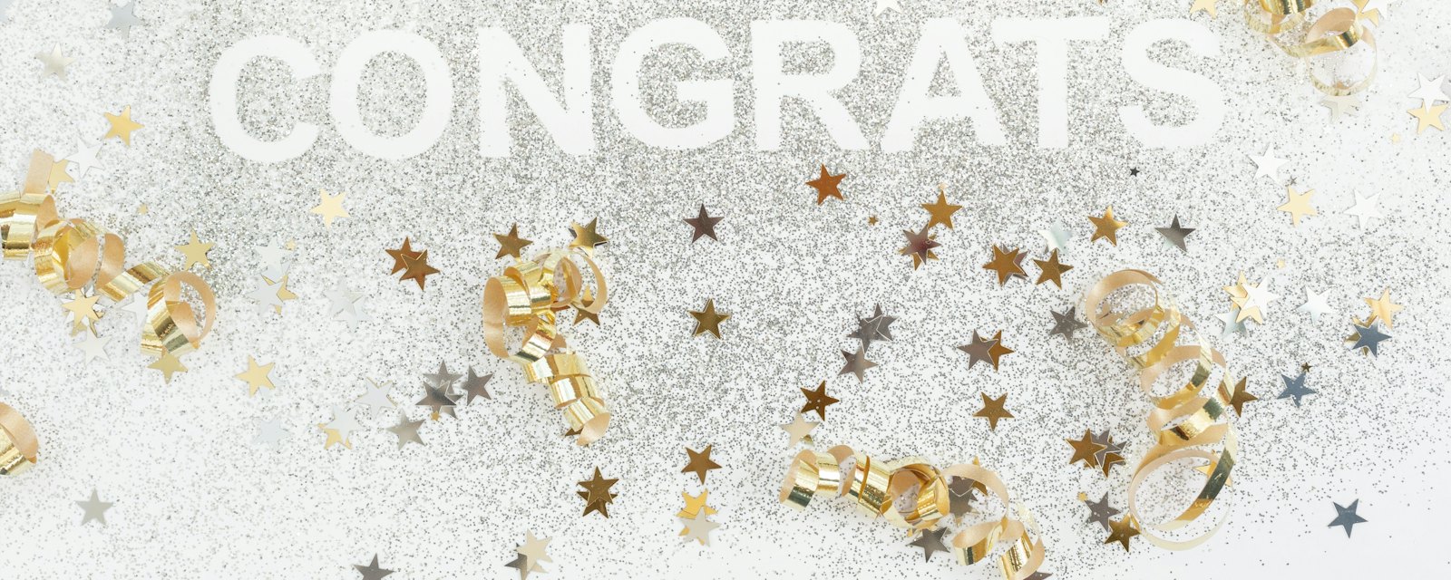 The word Congrats surrounded by gold ribbons and star confetti