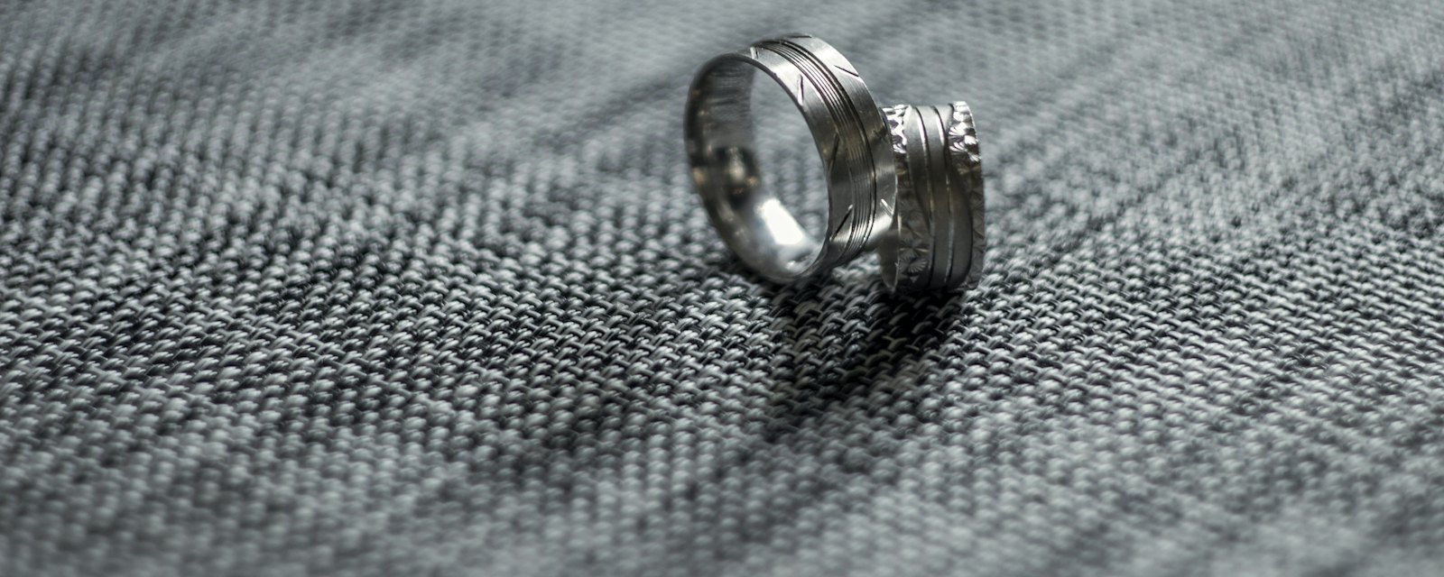 Two silver wedding rings on a grey textured surface