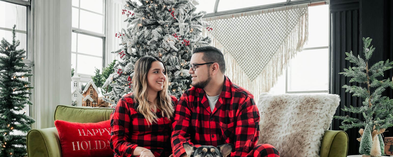 A couple in matching tartan pyjamas relaxing by a Christmas tree