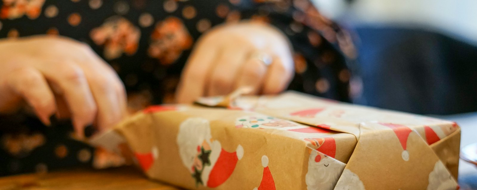 Hands wrapping a Christmas present in festive brown paper