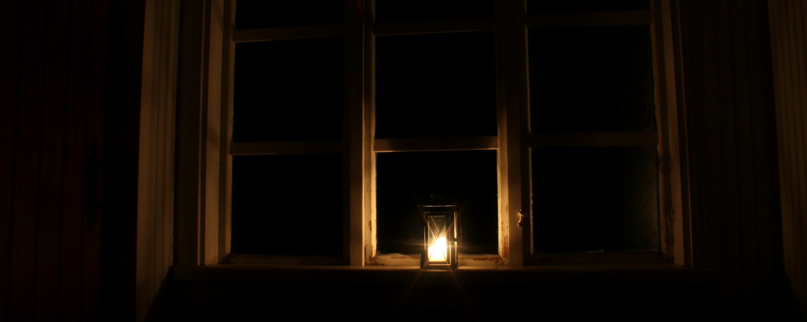 A single candle glowing in a window at night