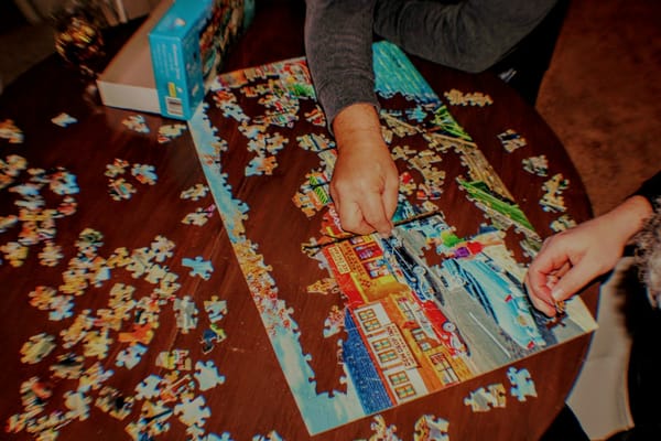 Hands fitting pieces into a colourful jigsaw puzzle
