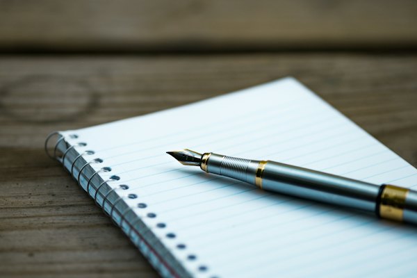 A fountain pen resting on an open notebook